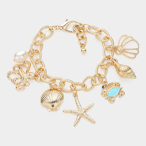 Gold bracelet with sea creature charms and pearl on white stone background