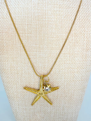 Gold chain necklace with large starfish pendant on neutral display bust