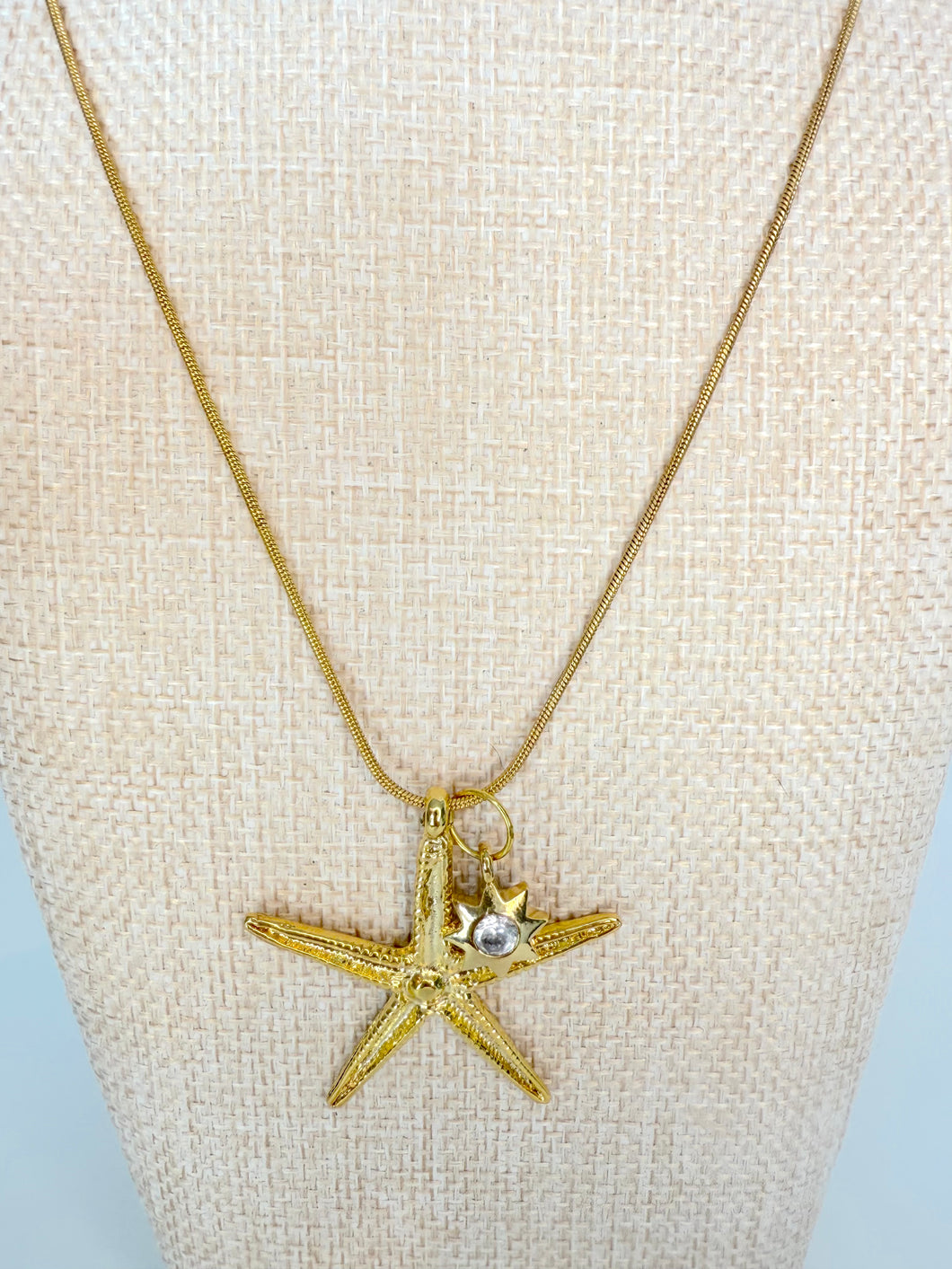 Gold chain necklace with large starfish pendant on neutral display bust